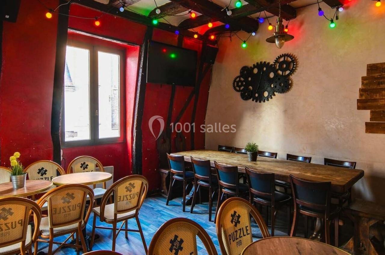 Salle colorée avec des tables en bois, chaises en osier, guirlandes lumineuses et décoration murale industrielle.
