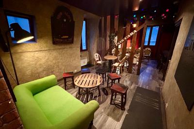 Terrasse de café avec des chaises en osier, tables vides et parasols, située dans une rue pavée bordée de bâtiments.