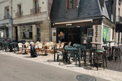 Grande table en bois massif entourée de chaises dans une pièce aux murs rouges avec poutres apparentes.