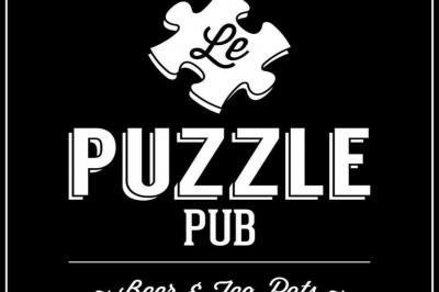 Grande table en bois massif entourée de chaises dans une pièce aux murs rouges avec poutres apparentes.