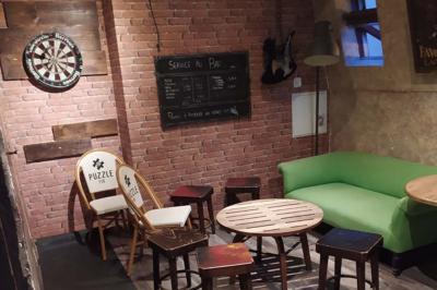 Grande table en bois massif entourée de chaises dans une pièce aux murs rouges avec poutres apparentes.