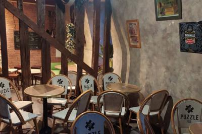 Grande table en bois massif entourée de chaises dans une pièce aux murs rouges avec poutres apparentes.