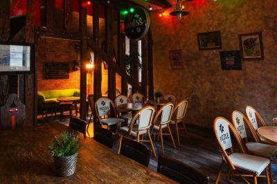 Grande table en bois massif entourée de chaises dans une pièce aux murs rouges avec poutres apparentes.