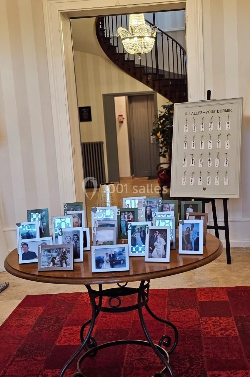 Table ronde avec des cadres photo disposés, devant un tableau indiquant des emplacements de couchage, dans une pièce…