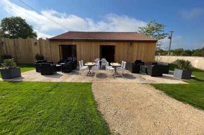 Vue aérienne d'un manoir entouré de jardins, avec des bâtiments annexes et des champs à proximité.