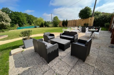 Vue aérienne d'un manoir entouré de jardins, avec des bâtiments annexes et des champs à proximité.