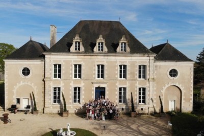 Vue aérienne d'un manoir entouré de jardins, avec des bâtiments annexes et des champs à proximité.