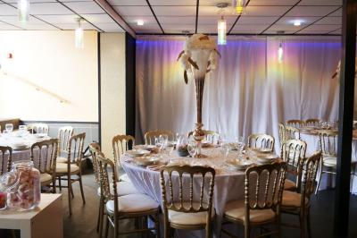 Terrasse en bois avec fauteuils, pergola à rideaux blancs, plantes en pot et mur en briques en arrière-plan.