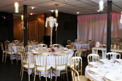 Terrasse en bois avec fauteuils, pergola à rideaux blancs, plantes en pot et mur en briques en arrière-plan.