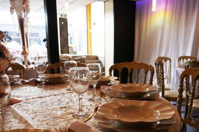 Terrasse en bois avec fauteuils, pergola à rideaux blancs, plantes en pot et mur en briques en arrière-plan.