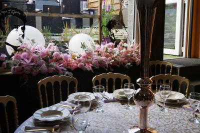 Terrasse en bois avec fauteuils, pergola à rideaux blancs, plantes en pot et mur en briques en arrière-plan.