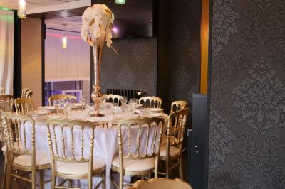 Terrasse en bois avec fauteuils, pergola à rideaux blancs, plantes en pot et mur en briques en arrière-plan.