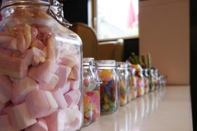 Terrasse en bois avec fauteuils, pergola à rideaux blancs, plantes en pot et mur en briques en arrière-plan.