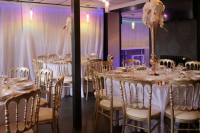 Terrasse en bois avec fauteuils, pergola à rideaux blancs, plantes en pot et mur en briques en arrière-plan.