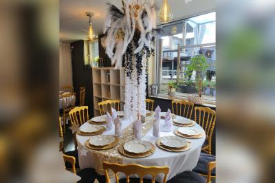 Terrasse en bois avec fauteuils, pergola à rideaux blancs, plantes en pot et mur en briques en arrière-plan.