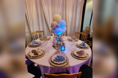 Terrasse en bois avec fauteuils, pergola à rideaux blancs, plantes en pot et mur en briques en arrière-plan.