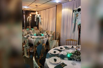 Terrasse en bois avec fauteuils, pergola à rideaux blancs, plantes en pot et mur en briques en arrière-plan.