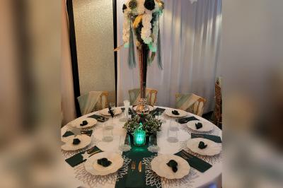 Terrasse en bois avec fauteuils, pergola à rideaux blancs, plantes en pot et mur en briques en arrière-plan.