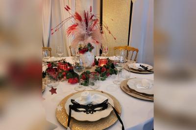 Terrasse en bois avec fauteuils, pergola à rideaux blancs, plantes en pot et mur en briques en arrière-plan.