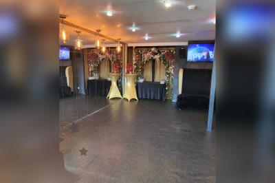 Terrasse en bois avec fauteuils, pergola à rideaux blancs, plantes en pot et mur en briques en arrière-plan.