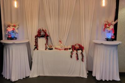 Terrasse en bois avec fauteuils, pergola à rideaux blancs, plantes en pot et mur en briques en arrière-plan.