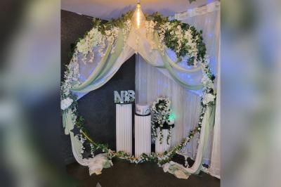 Terrasse en bois avec fauteuils, pergola à rideaux blancs, plantes en pot et mur en briques en arrière-plan.