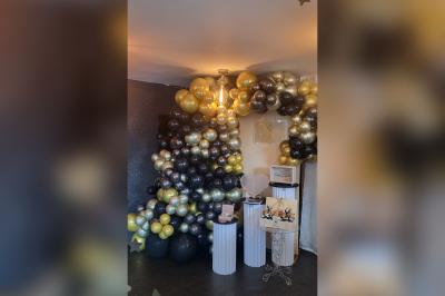 Terrasse en bois avec fauteuils, pergola à rideaux blancs, plantes en pot et mur en briques en arrière-plan.