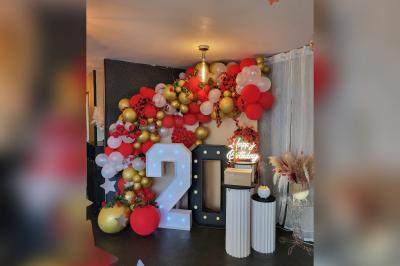 Terrasse en bois avec fauteuils, pergola à rideaux blancs, plantes en pot et mur en briques en arrière-plan.