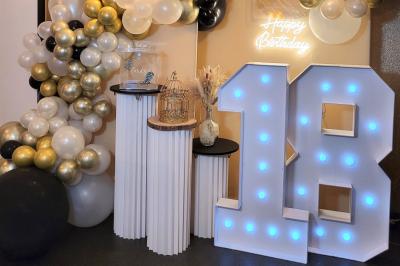 Terrasse en bois avec fauteuils, pergola à rideaux blancs, plantes en pot et mur en briques en arrière-plan.