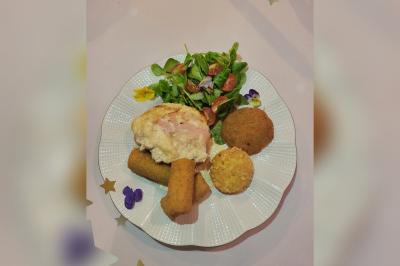 Terrasse en bois avec fauteuils, pergola à rideaux blancs, plantes en pot et mur en briques en arrière-plan.