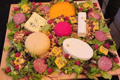 Terrasse en bois avec fauteuils, pergola à rideaux blancs, plantes en pot et mur en briques en arrière-plan.