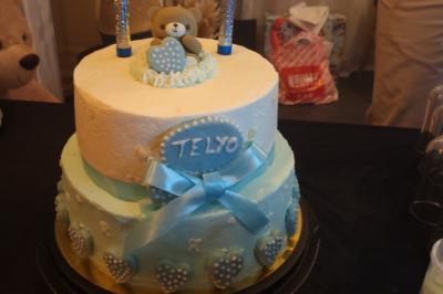 Terrasse en bois avec fauteuils, pergola à rideaux blancs, plantes en pot et mur en briques en arrière-plan.