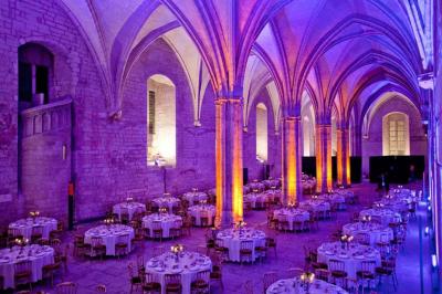 Vue nocturne d'un jardin avec des invités rassemblés lors d'un événement, éclairé par des lumières chaleureuses.