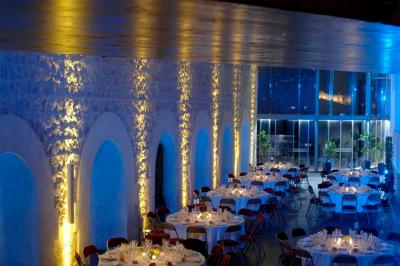 Vue nocturne d'un jardin avec des invités rassemblés lors d'un événement, éclairé par des lumières chaleureuses.