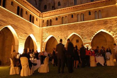 Vue nocturne d'un jardin avec des invités rassemblés lors d'un événement, éclairé par des lumières chaleureuses.
