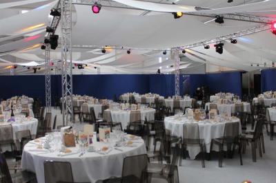 Vue nocturne d'un jardin avec des invités rassemblés lors d'un événement, éclairé par des lumières chaleureuses.