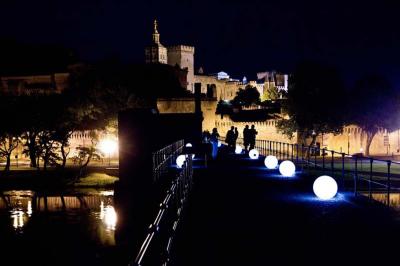 Vue nocturne d'un jardin avec des invités rassemblés lors d'un événement, éclairé par des lumières chaleureuses.