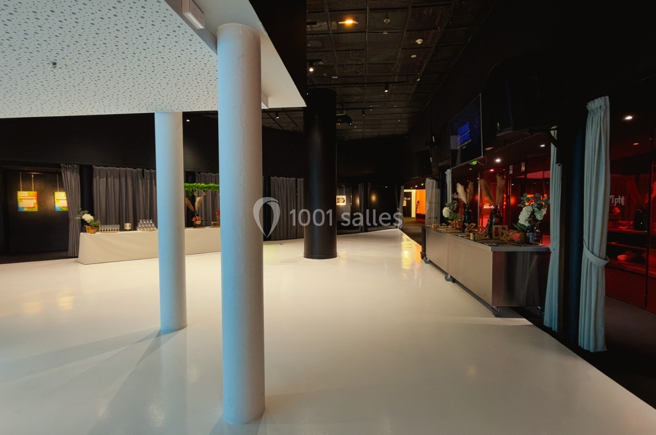 Espace intérieur moderne avec sol blanc brillant, colonnes blanches et stands d'exposition éclairés.