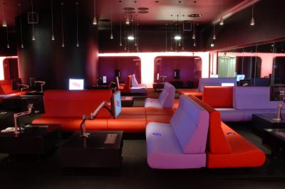 Espace intérieur moderne avec canapés colorés, éclairage suspendu et logo ’TUMO Paris’ sur un mur noir.