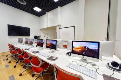 Espace intérieur moderne avec canapés colorés, éclairage suspendu et logo ’TUMO Paris’ sur un mur noir.