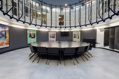 Espace intérieur moderne avec canapés colorés, éclairage suspendu et logo ’TUMO Paris’ sur un mur noir.