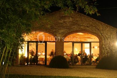 Façade d'une maison ancienne avec volets en bois, entourée de végétation sous un ciel dégagé.