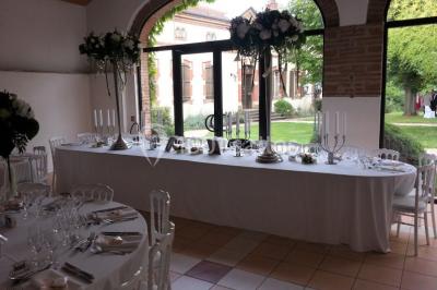 Façade d'une maison ancienne avec volets en bois, entourée de végétation sous un ciel dégagé.
