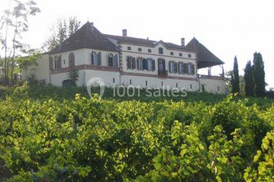 Façade d'un bâtiment en pierre avec grandes fenêtres, tables dressées à l'extérieur et tente blanche sur la droite.