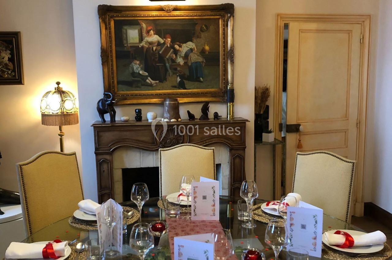 Table dressée avec élégance dans une salle à manger décorée, avec un tableau ancien au-dessus d'une cheminée.