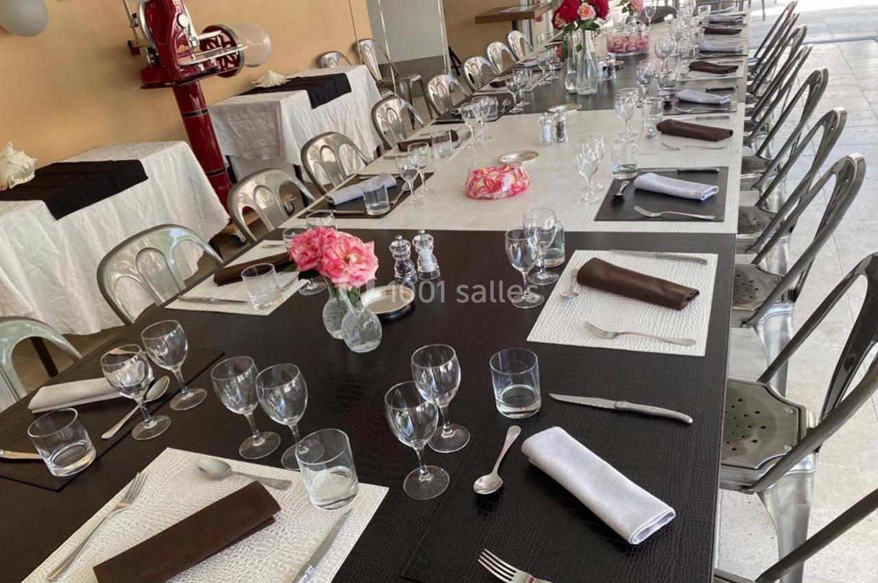 Table dressée pour un repas, avec nappes noires et blanches, couverts, verres et décorations florales.