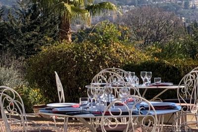 Vue sur un jardin verdoyant avec des arbres et des collines en arrière-plan sous un ciel dégagé.