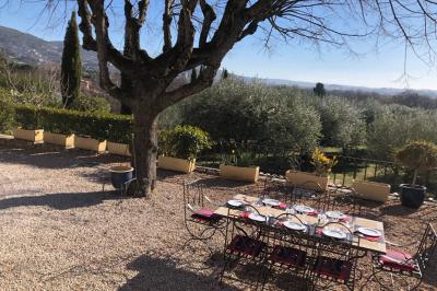 Vue sur un jardin verdoyant avec des arbres et des collines en arrière-plan sous un ciel dégagé.