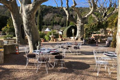 Vue sur un jardin verdoyant avec des arbres et des collines en arrière-plan sous un ciel dégagé.