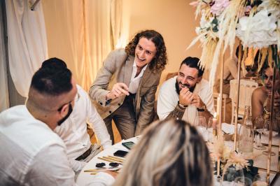 Miniature Robin Geyer - Magicien Professionnel Français #2 Un homme en costume parle avec animation à une femme souriante dans un café, entourés de mains applaudissant.